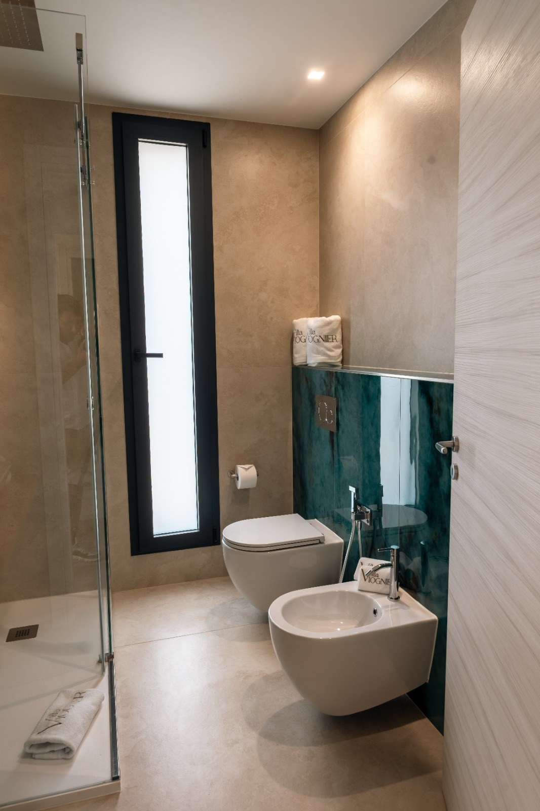 Il bagno di Malvasia con rivestimenti verdi e finestra
